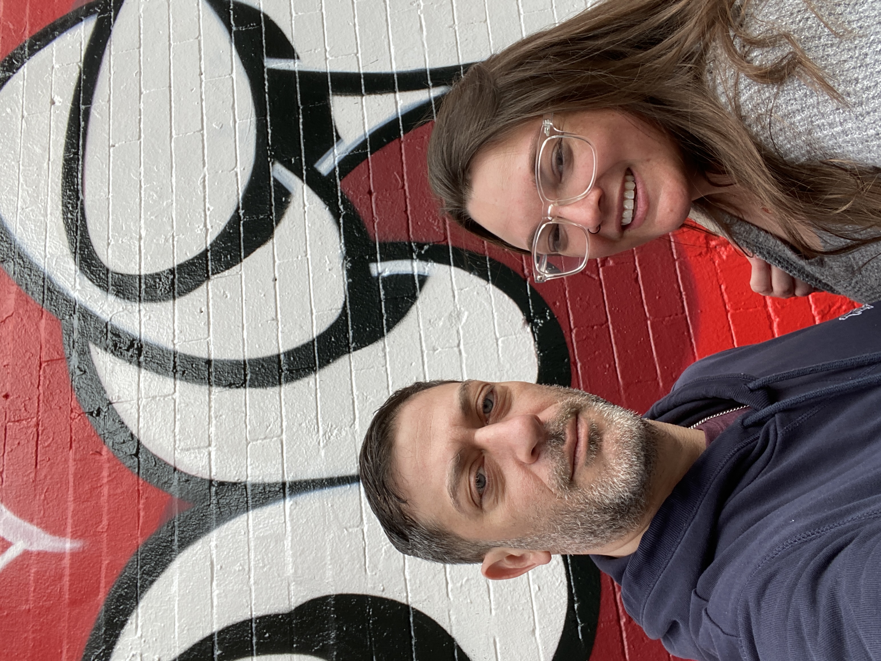 David and Gina standing in front of a red, white, and black mural in Lower Manhattan