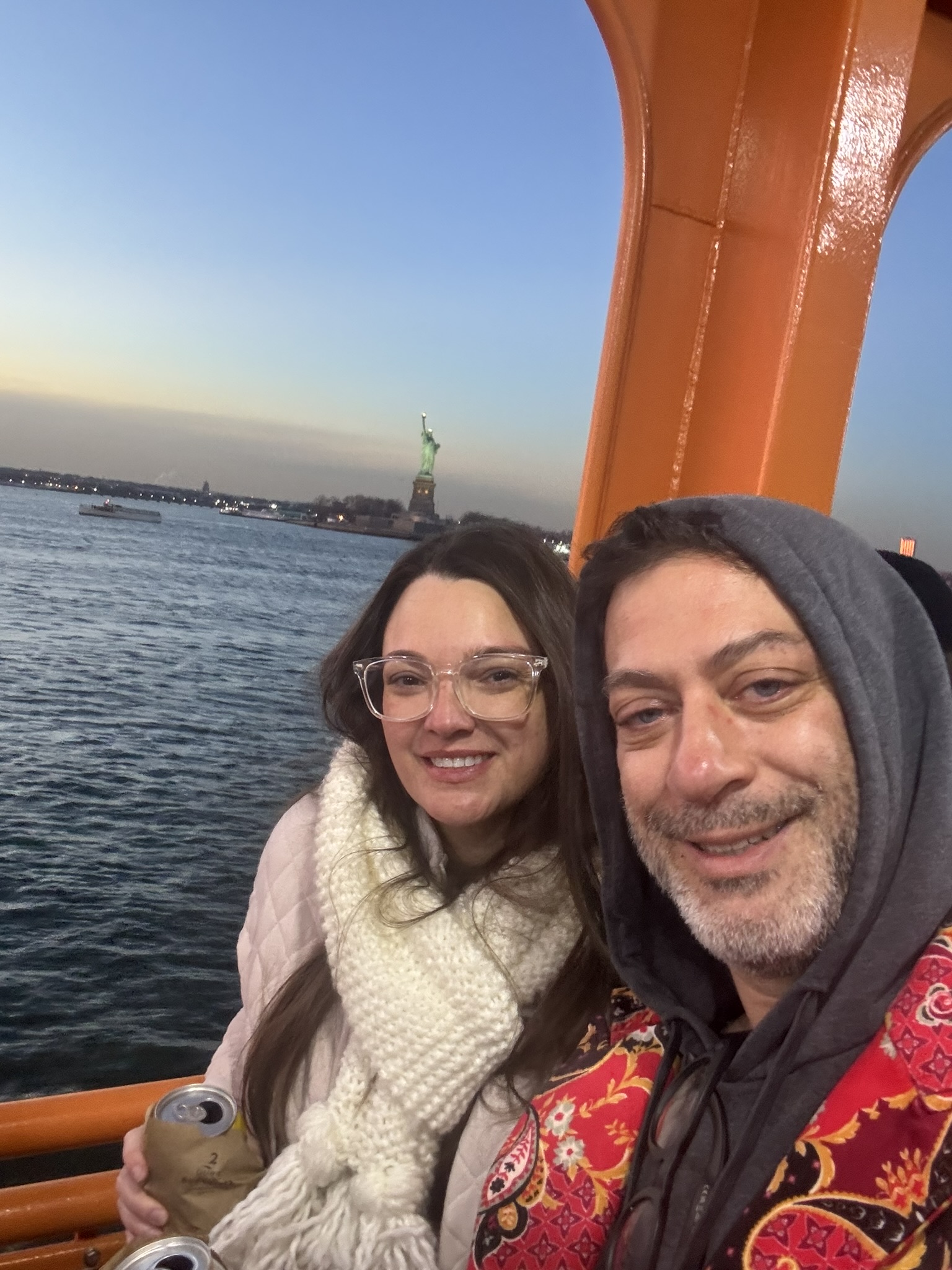 Gina and David on a ferry with the Statue of Liberty behind them at dusk